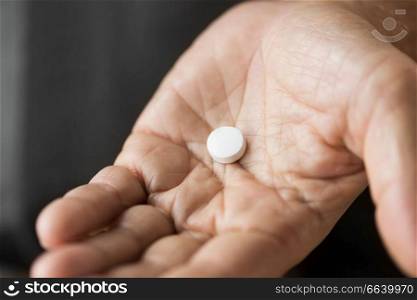 medicine, healthcare and people concept - close up of senior man hand with pill. close up of senior man hand with pill