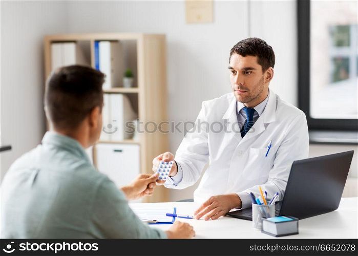 medicine, healthcare and people concept - doctor giving pills to male patient at medical office in hospital. doctor giving medicine to male patient at hospital