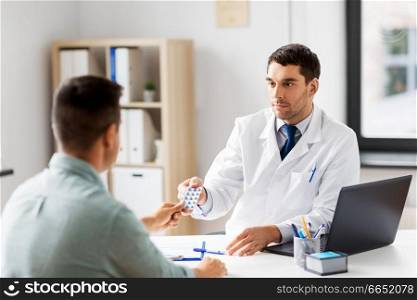 medicine, healthcare and people concept - doctor giving pills to male patient at medical office in hospital. doctor giving medicine to male patient at hospital
