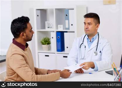 medicine, healthcare and people concept - doctor giving prescription to male patient at clinic. doctor and male patient meeting at clinic