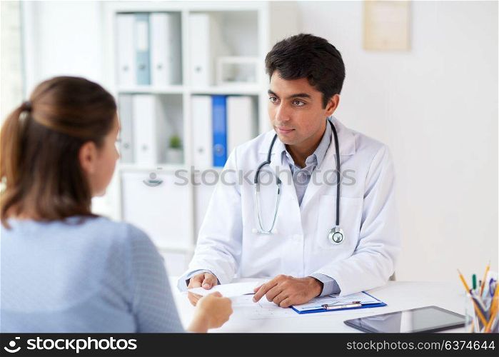 medicine, healthcare and people concept - doctor giving prescription to patient at hospital. doctor giving prescription to patient at hospital