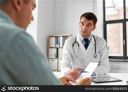 medicine, healthcare and people concept - doctor giving prescription to patient at medical office in hospital. doctor giving prescription to patient at hospital