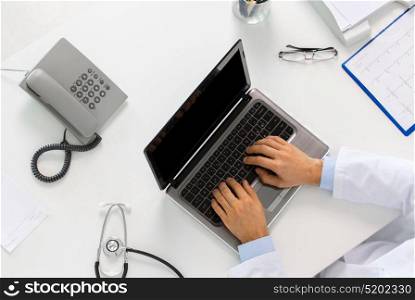 medicine, healthcare and people concept - doctor hands typing on laptop computer sitting at table in clinic. doctor hands typing on laptop at clinic