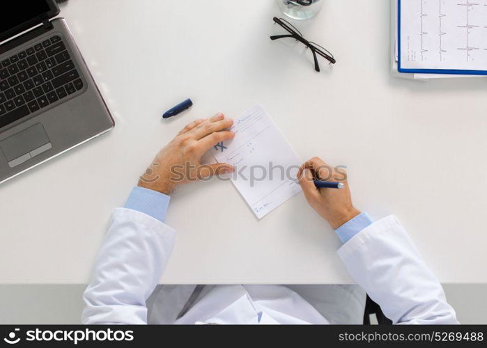 medicine, healthcare and people concept - doctor hands with prescription at table in clinic. doctor hands with prescription at clinic