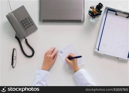 medicine, healthcare and people concept - doctor hands writing prescription at table. doctor hands writing prescription at table