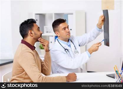 medicine, healthcare and people concept - doctor or surgeon with x-ray and male patient at clinic. doctor with x-ray and male patient at clinic