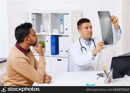 medicine, healthcare and people concept - doctor or surgeon with x-ray and male patient at clinic. doctor with x-ray and male patient at clinic