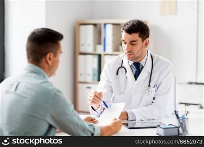 medicine, healthcare and people concept - doctor showing prescription to patient at medical office in hospital. doctor showing prescription to patient at hospital