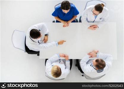 medicine, healthcare and people concept - doctor showing something imaginary on table. doctor showing something imaginary on table