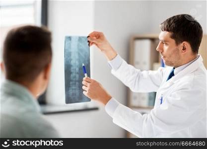 medicine, healthcare and people concept - doctor showing x-ray to patient at medical office in hospital. doctor showing x-ray to patient at hospital