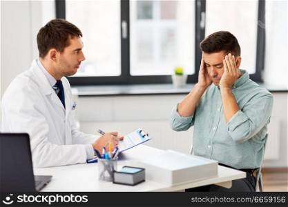 medicine, healthcare and people concept - doctor with clipboard and male patient suffering from sick headache at medical office in hospital. doctor and male patient having headache at clinic