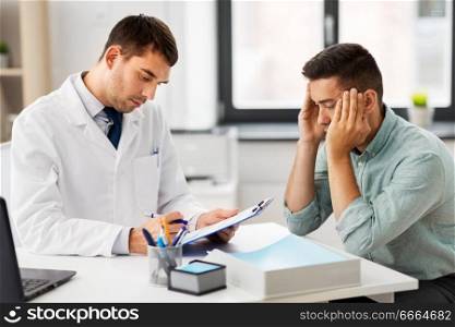 medicine, healthcare and people concept - doctor with clipboard and male patient suffering from headache at medical office in hospital. doctor with clipboard and male patient at hospital
