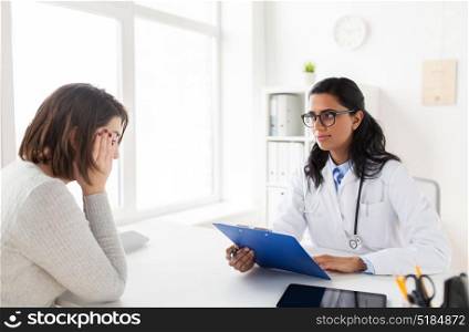 medicine, healthcare and people concept - doctor with clipboard and sad woman patient at hospital. doctor with clipboard and woman patient at clinic