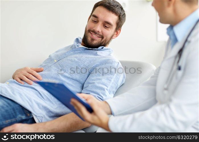 medicine, healthcare and people concept - doctor with clipboard and smiling young male patient at medical exam at hospital. doctor and man with health problem at hospital