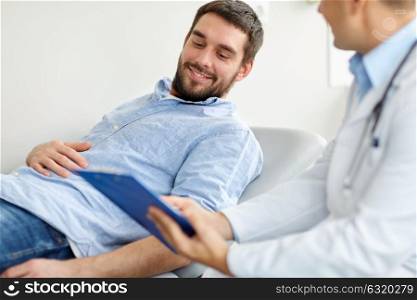 medicine, healthcare and people concept - doctor with clipboard and smiling young male patient at medical exam at hospital. doctor and man with health problem at hospital