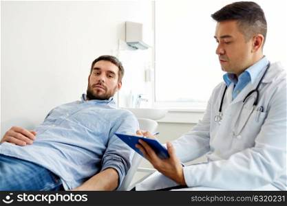 medicine, healthcare and people concept - doctor with clipboard and young male patient having health problem meeting at hospital. doctor and man with health problem at hospital
