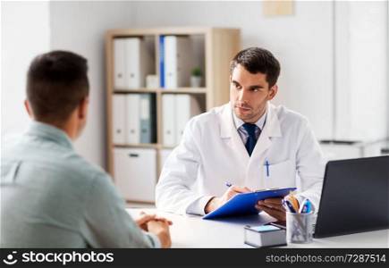 medicine, healthcare and people concept - doctor with clipboard talking to male patient at medical office in hospital. doctor with clipboard and male patient at hospital