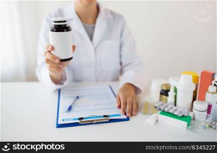 medicine, healthcare and people concept - doctor with drugs and clipboard showing jar with medication. close up of doctor with medicines and clipboard