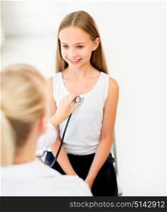 medicine, healthcare and people concept - doctor with stethoscope listening to girl heart beat or breath at hospital. doctor with stethoscope and girl at hospital