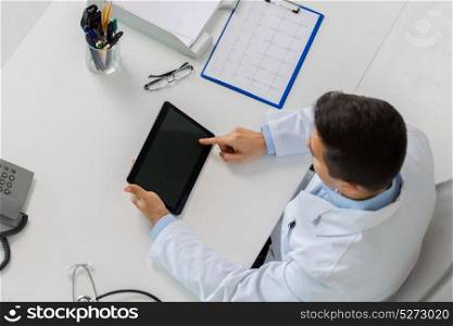 medicine, healthcare and people concept - doctor with tablet pc computer and cardiogram sitting at table in clinic. doctor with tablet pc and cardiogram at clinic