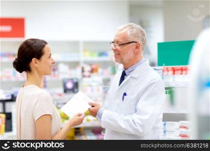 medicine, healthcare and people concept - female customer giving prescription to senior apothecary at pharmacy. woman and apothecary with prescription at pharmacy