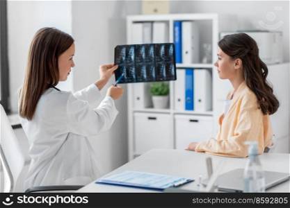medicine, healthcare and people concept - female doctor or vertebrologist showing x-ray image of spine to woman patient at hospital. doctor showing x-ray image to woman at hospital
