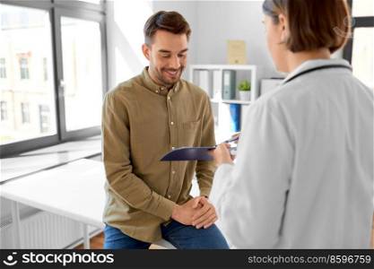 medicine, healthcare and people concept - female doctor showing clipboard to smiling man patient at hospital. doctor showing clipboard to patient at hospital