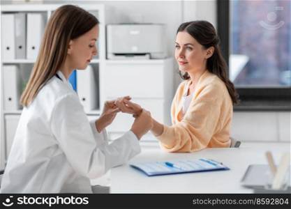 medicine, healthcare and people concept - female doctor taking woman patient’s pulse at hospital. female doctor taking patient’s pulse at clinic