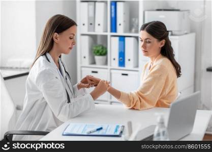 medicine, healthcare and people concept - female doctor taking woman patient’s pulse at hospital. female doctor taking patient’s pulse at clinic