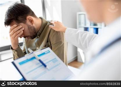 medicine, healthcare and people concept - female doctor with clipboard comforting sad male patient having health problem at hospital. doctor and sad man with health problem at hospital