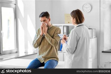 medicine, healthcare and people concept - female doctor with clipboard talking to man patient blowing his nose with paper tissue at hospital. female doctor and man blowing nose at hospital