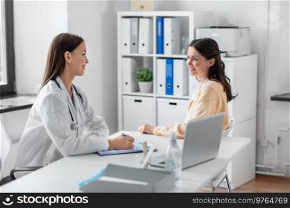 medicine, healthcare and people concept - female doctor with clipboard talking to smiling woman patient at hospital. female doctor and woman patient meeting at clinic