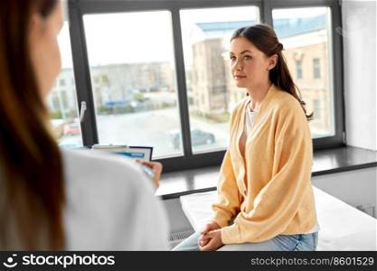 medicine, healthcare and people concept - female doctor with clipboard talking to woman patient at hospital. doctor with clipboard and woman at hospital