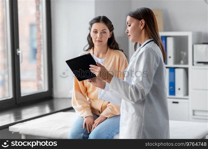 medicine, healthcare and people concept - female doctor with tablet pc computer talking to woman patient at hospital. female doctor with tablet pc and woman at hospital