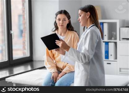 medicine, healthcare and people concept - female doctor with tablet pc computer talking to woman patient at hospital. female doctor with tablet pc and woman at hospital
