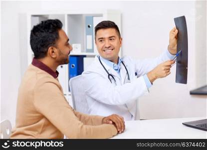 medicine, healthcare and people concept - happy doctor or surgeon showing x-ray to male patient at clinic. doctor with x-ray and male patient at clinic