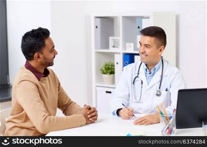 medicine, healthcare and people concept - happy doctor writing prescription for male patient at clinic. happy doctor and male patient meeting at clinic