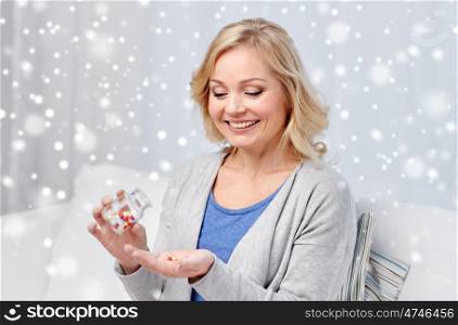 medicine, healthcare and people concept - happy middle aged woman with medication at home over snow