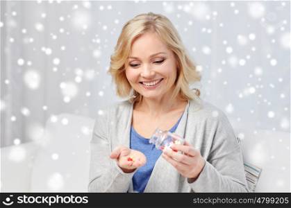 medicine, healthcare and people concept - happy middle aged woman with medication at home over snow
