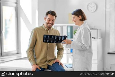 medicine, healthcare and people concept - happy smiling female doctor showing x-ray to male patient at medical office in hospital. doctor showing x-ray to male patient at hospital