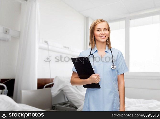 medicine, healthcare and people concept - happy smiling female doctor with clipboard over hospital ward background. female doctor with clipboard at hospital ward
