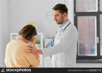 medicine, healthcare and people concept - male doctor with clipboard comforting sad woman patient having health problem at hospital. doctor comforting sad woman at hospital