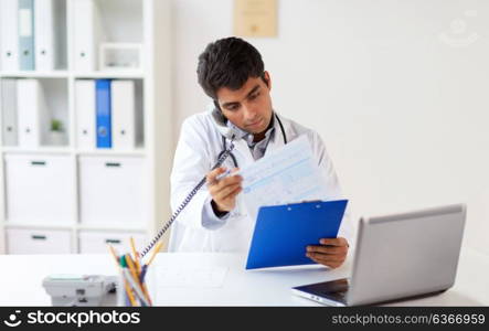 medicine, healthcare and people concept - male doctor with medical report calling on phone at clinic. doctor with clipboard calling on phone at clinic