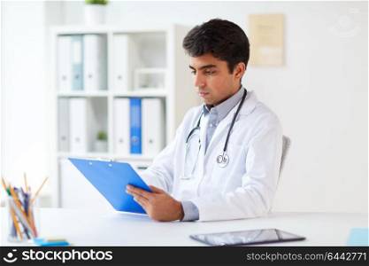 medicine, healthcare and people concept - male doctor with stethoscope and clipboard at clinic. doctor with clipboard at clinic