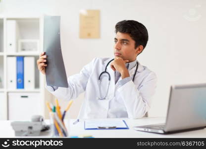 medicine, healthcare and people concept - male doctor with stethoscope looking spine at x-ray scan at clinic. doctor looking at spine x-ray scan at clinic