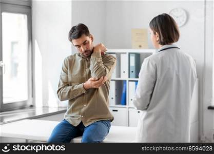 medicine, healthcare and people concept - male patient showing sore arm to female doctor at medical office in hospital. man patient showing sore arm to doctor at hospital
