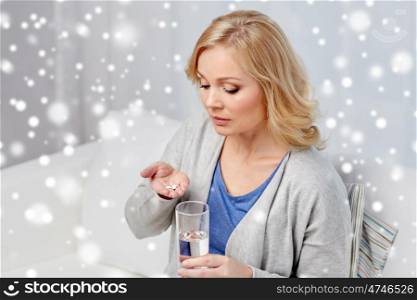medicine, healthcare and people concept - middle aged woman with medication and water glass at home over snow