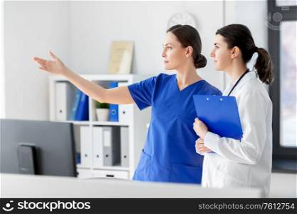 medicine, healthcare and people concept - nurse showing something to doctor with clipboard at hospital. nurse showing something to doctor at hospital