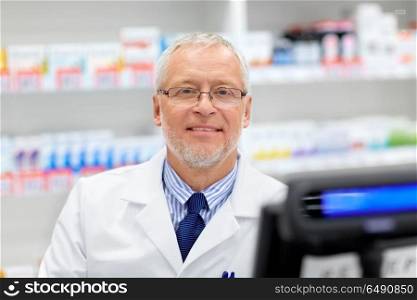 medicine, healthcare and people concept - senior apothecary at pharmacy cash register. senior apothecary at pharmacy cash register. senior apothecary at pharmacy cash register
