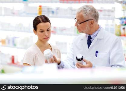 medicine, healthcare and people concept - senior apothecary with drug and female customer at pharmacy. apothecary and woman with drug at pharmacy. apothecary and woman with drug at pharmacy